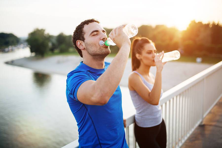 Couple staying hydrated after workout on a bridge