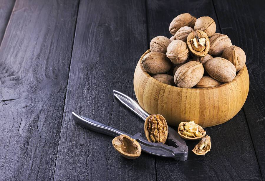Walnut kernels and whole walnuts on wooden background