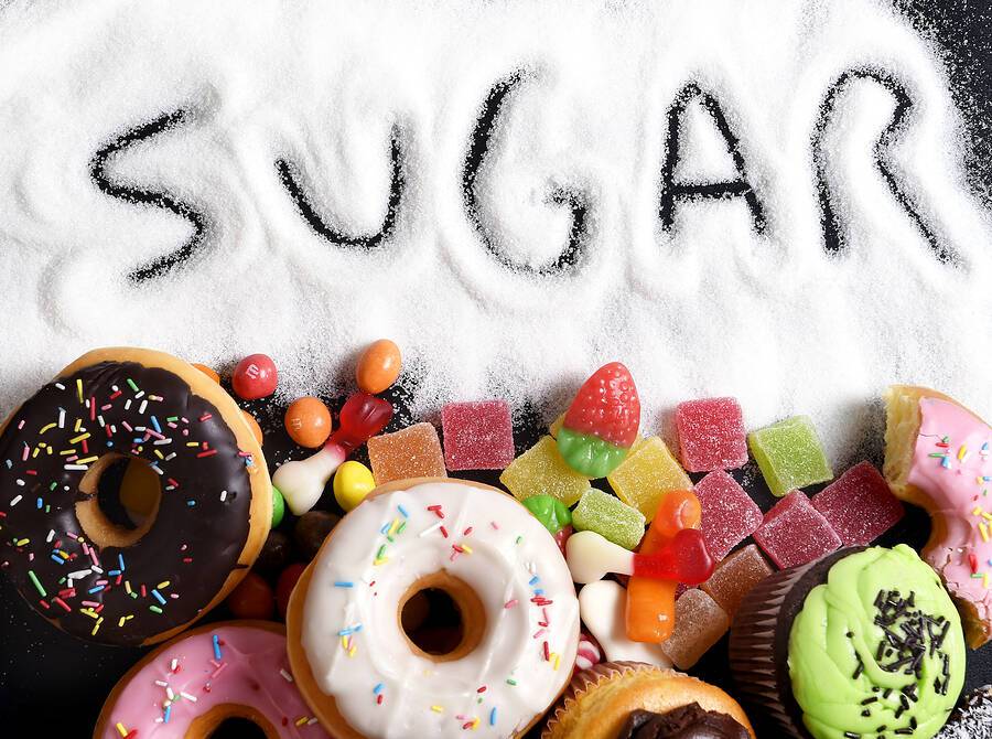 mix of sweet cakes donuts and candy with sugar spread and written text in unhealthy nutrition chocolate abuse and addiction concept body and dental care