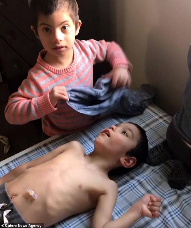 Simon Clark is just four-years-old, yet helps his PE teacher father Jeremy, 33, and nurse mother Nicole, 31, from Utah, feed and dress adopted brothers. He is seen dressingÃÂ Jon, six, who has Cerebral Palsy